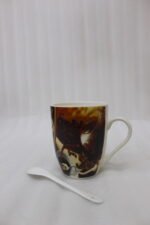 Ceramic mug featuring a full-wrap printed coffee bean and espresso graphic sitting on a kitchen counter next to a matching white ceramic spoon.
