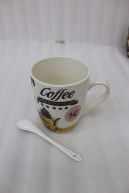 White printed ceramic coffee mug reading "Coffee and then the world" sitting on a granite countertop next to a small white spoon