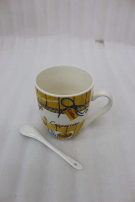 Printed ceramic coffee mug with vintage yellow wooden pattern, cappuccino text, coffee bean prints, and matching white spoon on a kitchen counter