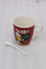 Red ceramic coffee mug with vintage coffee graphic print and matching white ceramic spoon on a kitchen counter