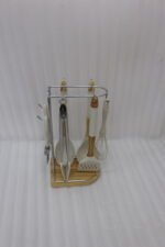 8 piece white silicone kitchen utensil set hanging on a stainless steel stand with wooden handles on a wooden countertop