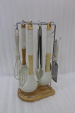 8 piece white silicone kitchen utensil set hanging on a stainless steel stand with wooden handles on a wooden countertop