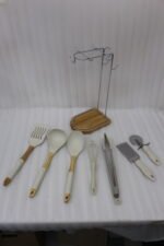8 piece white silicone kitchen utensil set hanging on a stainless steel stand with wooden handles on a wooden countertop
