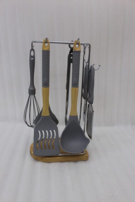 8 pcs grey silicone cooking utensils set with wooden handles hanging on a stainless steel stand with wooden base