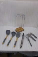 8 pcs grey silicone cooking utensils set with wooden handles hanging on a stainless steel stand with wooden base
