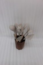 11-piece cream silicone kitchen utensil set with rose gold handles in a wooden holder on a marble countertop