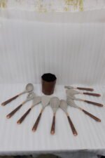 11-piece cream silicone kitchen utensil set with rose gold handles in a wooden holder on a marble countertop