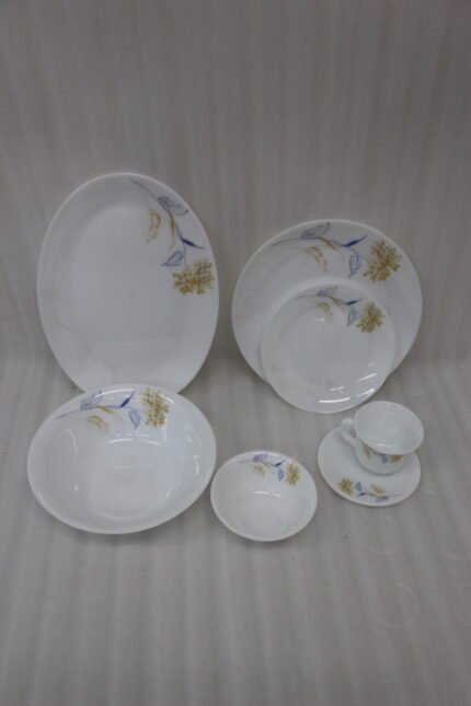 Elegant 32-piece white floral printed dinner set displayed on a marble countertop with plates, bowls, cups, and a platter
