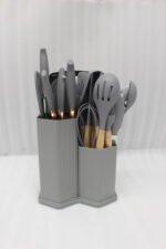 Grey 19-piece silicone kitchen utensil and knife set with wooden handles in a matching grey dual-compartment storage block.