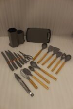 Grey 19-piece silicone kitchen utensil and knife set with wooden handles in a matching grey dual-compartment storage block.