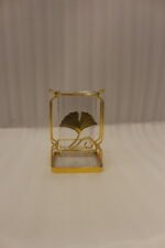 Luxury gold frame spoon stand with fluted clear acrylic container featuring a gold ginkgo leaf emblem on a marble countertop.