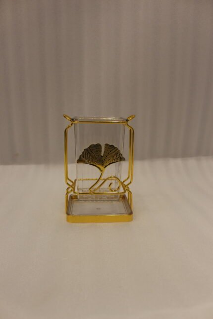 Luxury gold frame spoon stand with fluted clear acrylic container featuring a gold ginkgo leaf emblem on a marble countertop.
