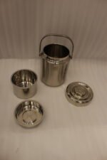 Polished insulated stainless steel lunch box container with a metal carrying handle on a kitchen countertop