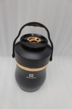 Matte black portable insulated lunch box jar with gold trim accent and black top handle on a kitchen counter