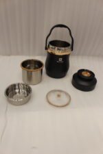 Matte black portable insulated lunch box jar with gold trim accent and black top handle on a kitchen counter