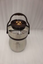 AILIJIN insulated stainless steel lunch box container with a dark brown carrying handle sitting on a modern kitchen countertop.