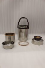 AILIJIN insulated stainless steel lunch box container with a dark brown carrying handle sitting on a modern kitchen countertop.