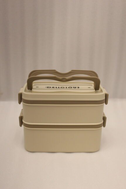 Beige and brown 2 in 1 double layer bento lunch box with locking latches on a kitchen counter
