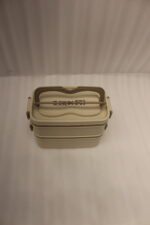 Beige and brown 2 in 1 double layer bento lunch box with locking latches on a kitchen counter