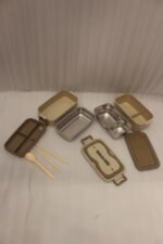 Beige and brown 2 in 1 double layer bento lunch box with locking latches on a kitchen counter