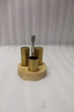 Brushed brass metal salt and pepper shakers with toothpick holder set in a round wooden base on a granite countertop
