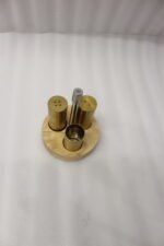 Brushed brass metal salt and pepper shakers with toothpick holder set in a round wooden base on a granite countertop