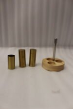 Brushed brass metal salt and pepper shakers with toothpick holder set in a round wooden base on a granite countertop