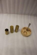 Brushed brass metal salt and pepper shakers with toothpick holder set in a round wooden base on a granite countertop