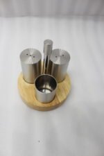 Stainless steel salt and pepper shakers with toothpick holder set in a wooden base on a marble kitchen countertop