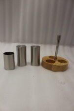 Stainless steel salt and pepper shakers with toothpick holder set in a wooden base on a marble kitchen countertop