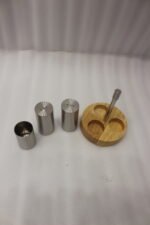 Stainless steel salt and pepper shakers with toothpick holder set in a wooden base on a marble kitchen countertop
