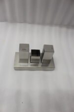 Brushed stainless steel rectangular salt and pepper shaker set with center holder on a matching metal base tray.