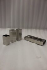 Brushed stainless steel rectangular salt and pepper shaker set with center holder on a matching metal base tray.