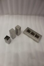Brushed stainless steel rectangular salt and pepper shaker set with center holder on a matching metal base tray.
