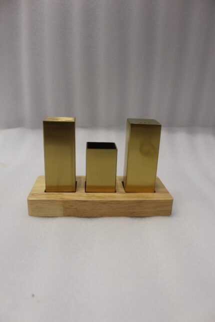 Modern brushed gold stainless steel salt and pepper shaker set with toothpick holder in a wooden base on a kitchen counter
