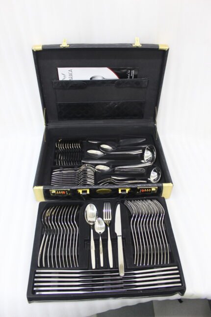 72-piece polished stainless steel cutlery set arranged on a cloth napkin featuring place settings, ladles, cake server, and tongs.