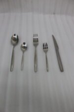 72-piece polished stainless steel cutlery set arranged on a cloth napkin featuring place settings, ladles, cake server, and tongs.
