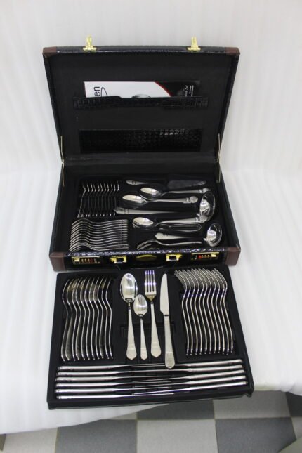 A Diverse Arrangement of Polished Silver-Toned Cutlery on a Textured Linen Mat, Featuring 12-Person Service and Loose Ladles, a Cake Server, and Tongs in the Background.