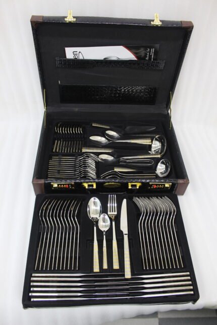 72-piece stainless steel cutlery and serving set with dual-tone gold textured handles laid out on a linen cloth.