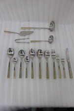 72-piece stainless steel cutlery and serving set with dual-tone gold textured handles laid out on a linen cloth.