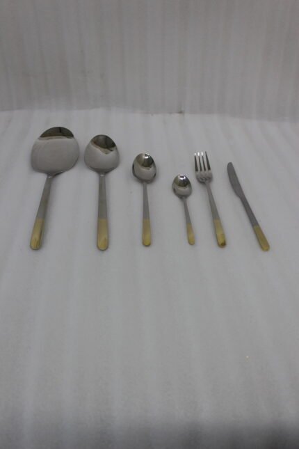 Stainless steel cutlery set with textured gold handles and floral engravings displayed on a beige cloth.