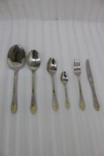 Six-piece luxury stainless steel cutlery set featuring textured handles with gold filigree details displayed on a beige linen napkin.