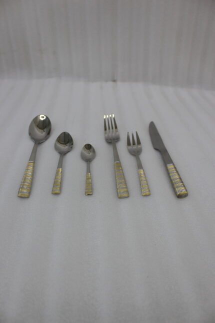 36-piece stainless steel cutlery set with two-tone gold and silver textured handles displayed on a beige napkin.