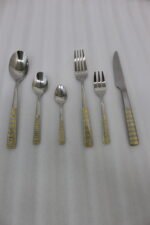 36-piece stainless steel cutlery set with two-tone gold and silver textured handles displayed on a beige napkin.