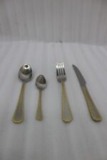 24-piece stainless steel cutlery set with gold-bordered handles including a rice spoon, sweet spoon, fork, and knife arranged on a grey placemat.