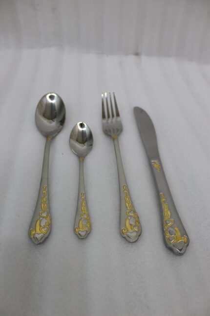 24 piece mirror polish stainless steel cutlery set with ornate gold heart handle detailing on a folded napkin