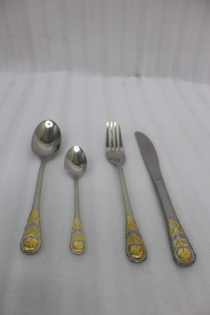 24 piece stainless steel cutlery set with gold rose embossed handles displayed on a cloth napkin