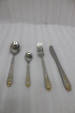 24-piece stainless steel cutlery set featuring gold "Love" engravings on handles, including rice spoon, sweet spoon, fork, and knife on a gray napkin.