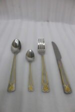 Stainless steel 24-piece cutlery set with gold-bordered handle and embossed flower design on linen napkin