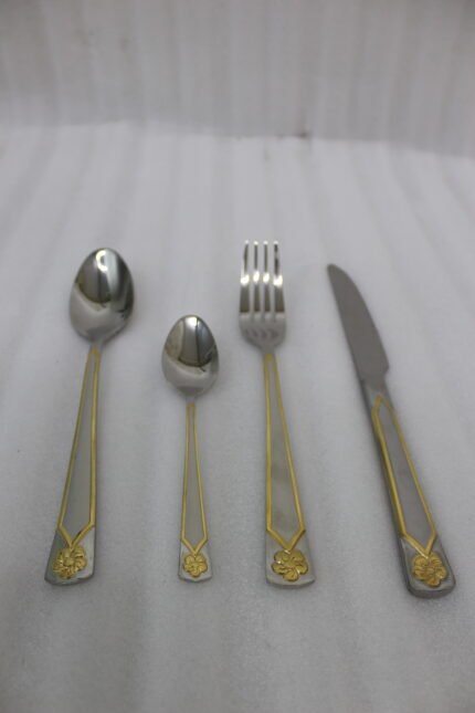 Stainless steel 24-piece cutlery set with gold-bordered handle and embossed flower design on linen napkin